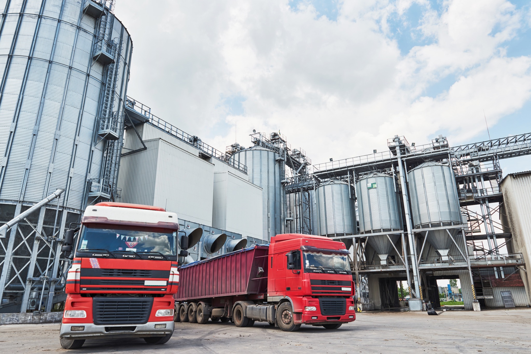 Cargo trucks beside agricultural storage silos